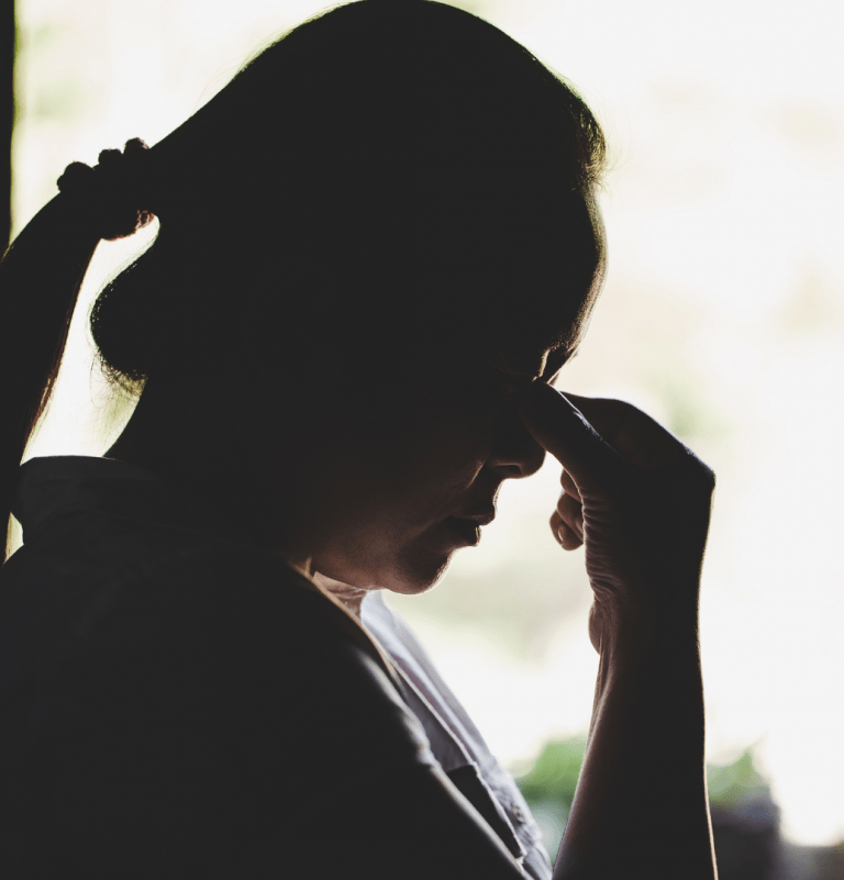 Woman appearing stressed, holding the bridge of her nose
