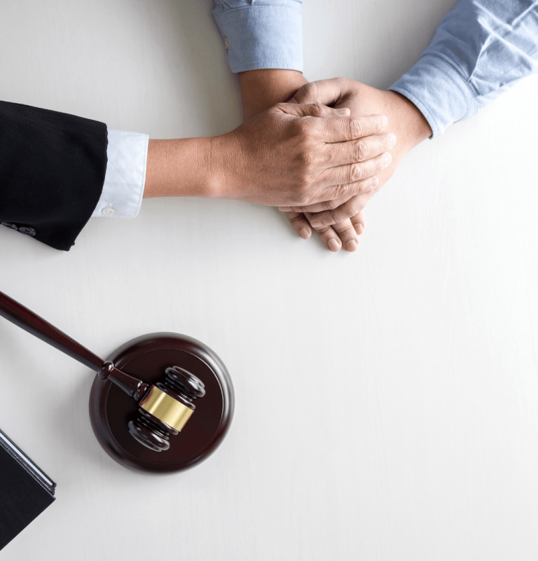 hands on top of someone elses hand with a gavel next to it