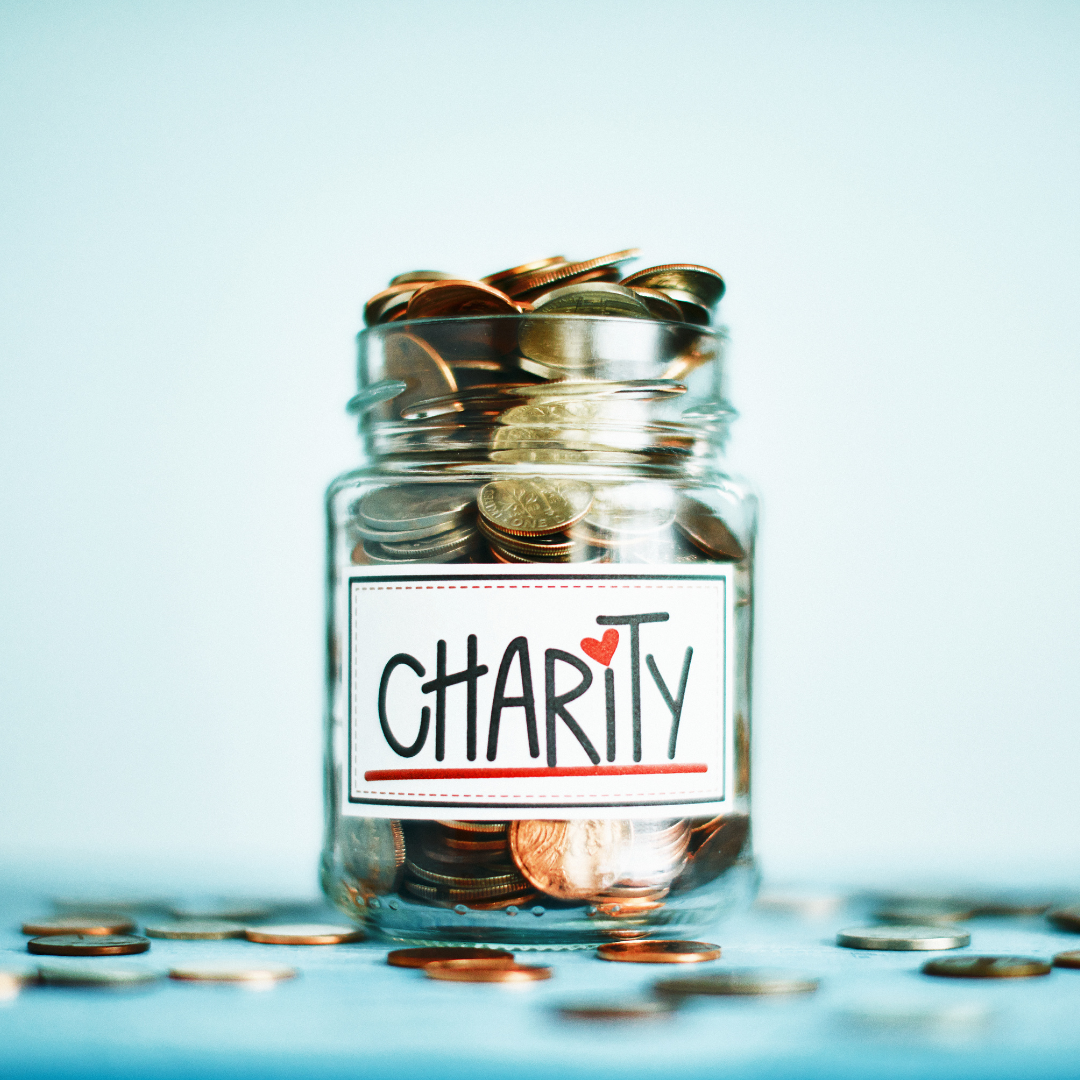 A Jar filled with coins that says Charity on the front