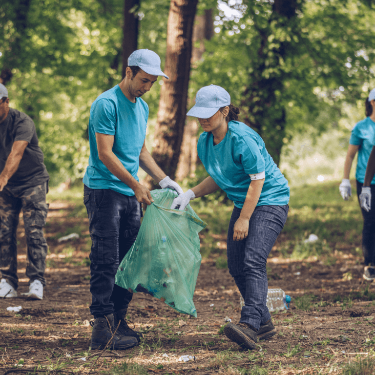 Photo of a man and a woman in matching uniforms picking up trash in a park